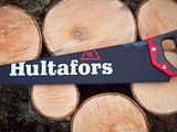 a black and red hand saw sitting on top of a pile of wood