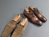 two pairs of brown shoes sitting on top of a gray surface