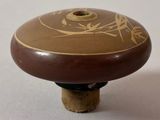 a small wooden object with a brown design on it