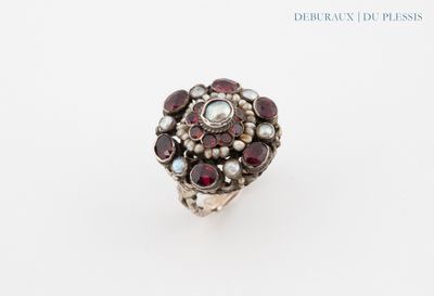 un gros plan d'une bague en argent sertie de grenats et de perles