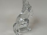 a glass figurine of a horse that is sitting on it ' s hind legs