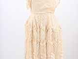 a white dress on a mannequin stand with a white background