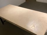 a wooden table with black legs in the middle of a room