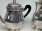 two silver teapots sitting next to each other on a table
