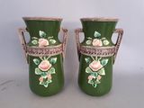 pair of green vases with pink roses on them sitting on a table