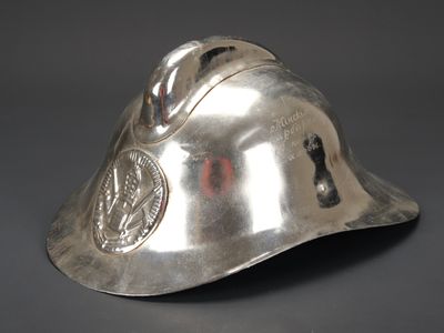 un vieux casque argenté orné d'un insigne, posé sur une surface grise