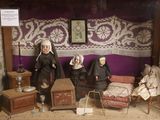 Les poupées sont exposées dans une vitrine, avec un mur violet en arrière-plan.