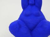 a blue sculpture of a man sitting on a white surface