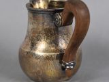 a silver pitcher with a wooden handle on a table