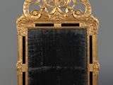 an ornately carved mirror with a gold frame on a grey background