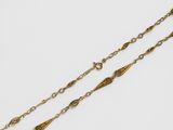 a gold plated necklace with a long chain that has been set on a white surface