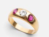 a close up of a yellow gold ring with a diamond and ruby stones