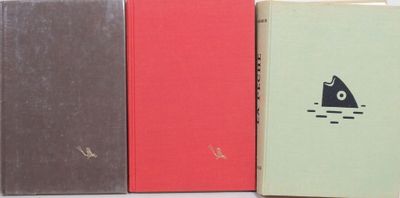 three books sitting next to each other on a white surface