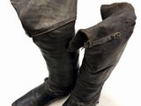 une paire de bottes en cuir noir posées sur une surface blanche, avec un fond blanc