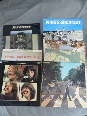 Plusieurs albums des Beatles sont posés sur un lit recouvert d'un drap blanc