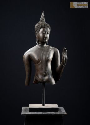 une statue en bronze représentant un Bouddha assis sur un fond noir