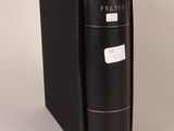 an old black book sitting on top of a table next to a white wall