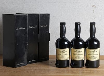 trois bouteilles de vin posées sur une table en bois, à côté d'une boîte
