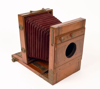 an old camera that is sitting on a wooden stand