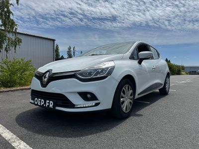 La voiture blanche est garée sur le parking près d'un immeuble.