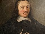 portrait of a man in a black coat and white collar holding his hands up