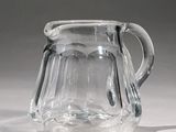 a clear glass pitcher with a handle on a table