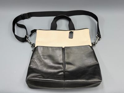 sac à main en cuir noir et blanc avec des fermetures éclair sur fond gris