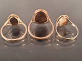 three gold rings with a brown stone in them on a table