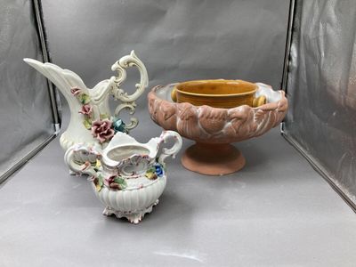 two vases and a bowl on display on a shelf