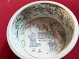 a small bowl with a painting on it sitting on a red surface