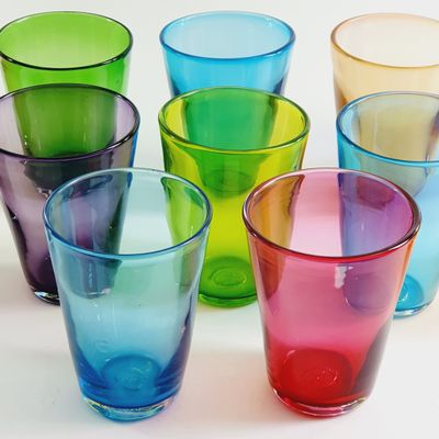 six different colored glasses sitting next to each other on a table