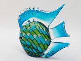 a blue and green glass fish figurine sitting on a white surface