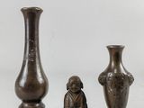 trois vases en bronze posés les uns à côté des autres sur une surface blanche