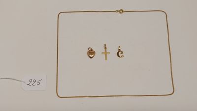 deux colliers en or et une paire de boucles d'oreilles posés sur une surface blanche
