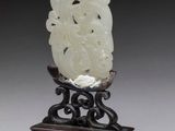 une image représentant une figurine en jade sculptée d'un homme posée sur un socle