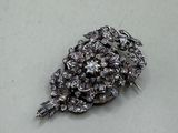 a silver brooch that has a bunch of flowers on it