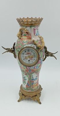 un vase surmonté d'une horloge, posé sur un socle