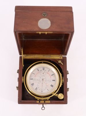une horloge dans un coffret en bois posé sur une surface blanche, avec un fond blanc