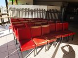 des rangées de chaises rouges disposées dans une pièce au sol carrelé de blanc