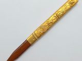 a gold pen with a wooden handle on a white surface