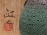 a green vase sitting on a table next to a box