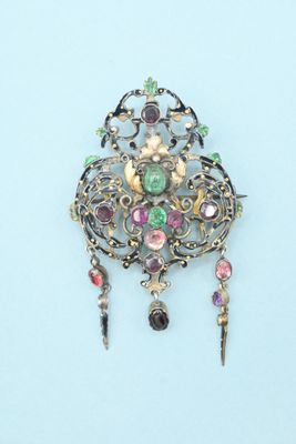 silver broochle with multi colored stones on it on a blue surface