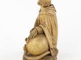 an antique statue of a man sitting on top of a ball