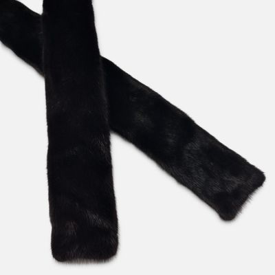 L'écharpe en fourrure noire est posée sur une surface blanche.