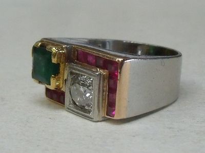 un gros plan d'une bague sertie d'un diamant, d'une émeraude et d'un rubis