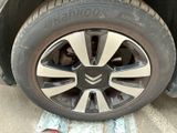 someone standing next to a car that has a tire on it ' s rim
