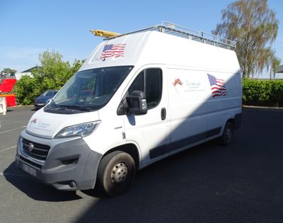 une camionnette blanche garée sur un parking, avec un drapeau sur le toit