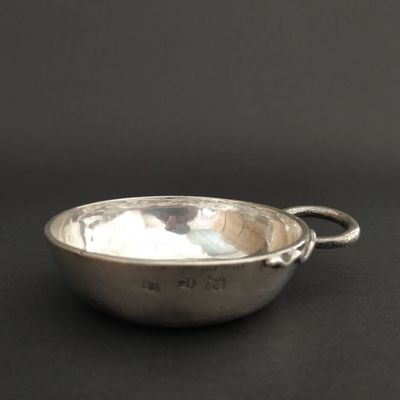 a silver bowl with a handle on a black surface