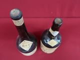 two bottles of wine sitting on a red surface