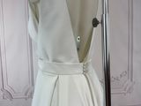 the back of a white wedding dress with a bow on a mannequin